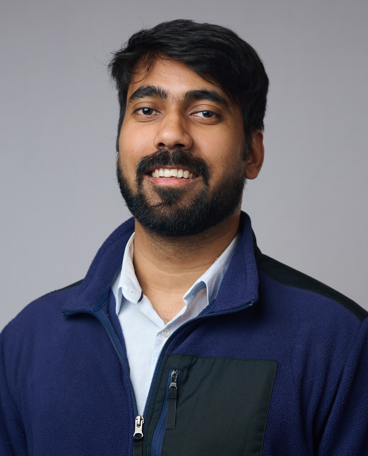 Amitesh Singh appears in a white collared shirt under a blue fleece.