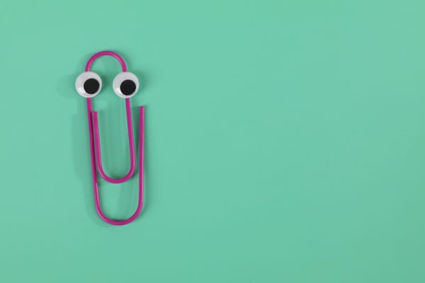 A purple paper clip that's slightly bent and has googly eyes pasted on sits atop a green background.